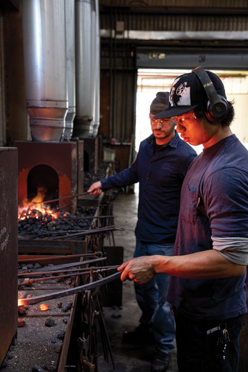 Blacksmithing professor Abe Pardee works with ACBA senior Emmett Sullivan; the school will unveil its new forge on upper King Street this month.