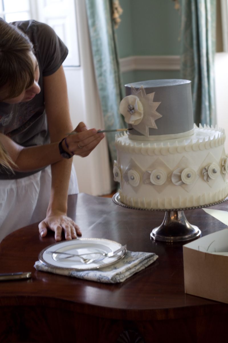 Hayden of Ashley Bakery left a repair kit for her cake, and in moving it, the icing got smudged, so Melissa tried to brush out the ripple. It may seems silly, but when you want a smoothly iced cake, sugar water and a paint brush and icing spatula are handy.