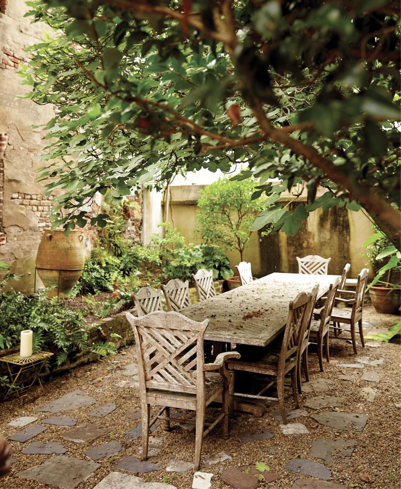 Garden Party - Tucked behind the patinaed stucco and brick of a Rainbow Row town house, this courtyard is a lovely alfresco dining room featuring potted citrus trees, such as lemon and tangerine.  Location: Rainbow Row (circa-1785 Georgian row house, then owned by Suzanne and Peter Pollak)  Issue: February 2017,  “Mix Master”  Photographer: Leigh Webber