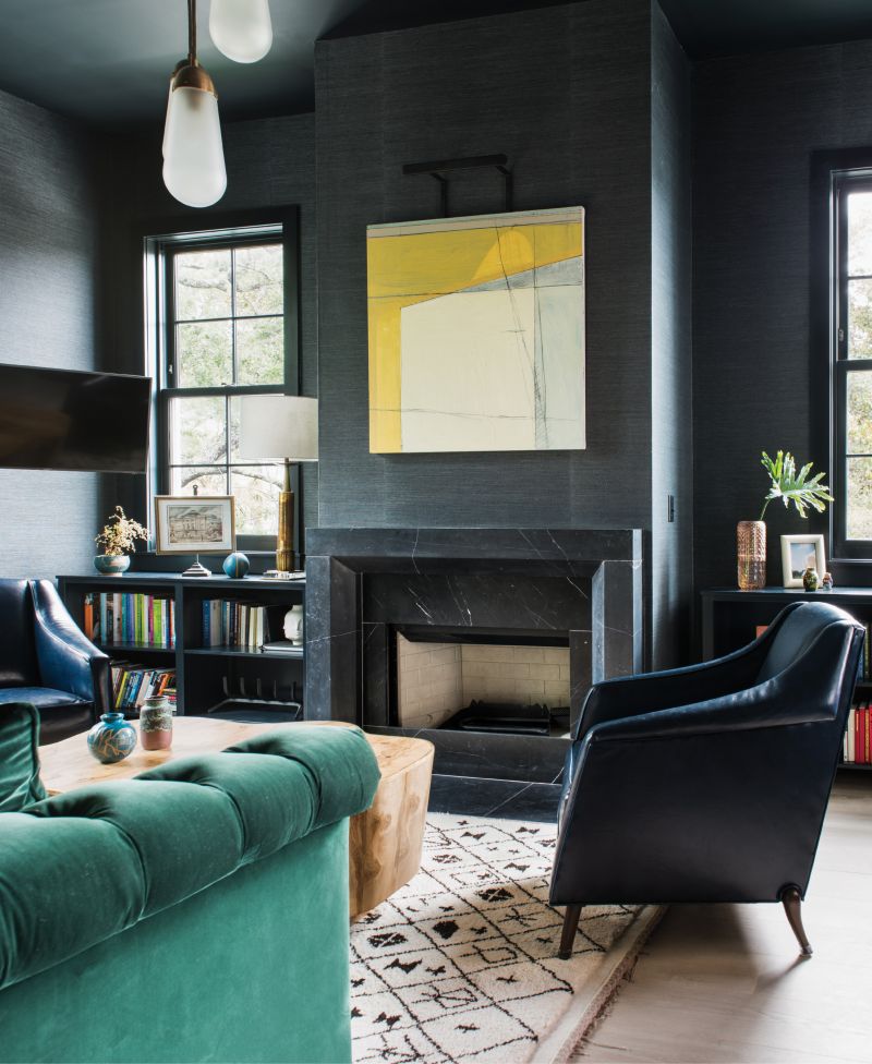 Amp Up the Ambiance - The rich hues and textures in this High Battery library beckon for hours of rest, reading, and relaxation. For this cozy-meetsmasculine space, interior designer Cortney Bishop covered the walls in Phillip Jeffries’s “Manila Hemp” paper in “charcoal” and had the Hickory Chair sofa upholstered in an emerald-green velvet by Ralph Lauren. Over the fireplace, an abstract work by Frank P. Phillips adds a sunny pop of color.  Location: Downtown, South  of Broad, owned by Molly and  Ted Fienning  Issue: March 2018, “High Style on the Battery”  Photographer: Katie Charlotte