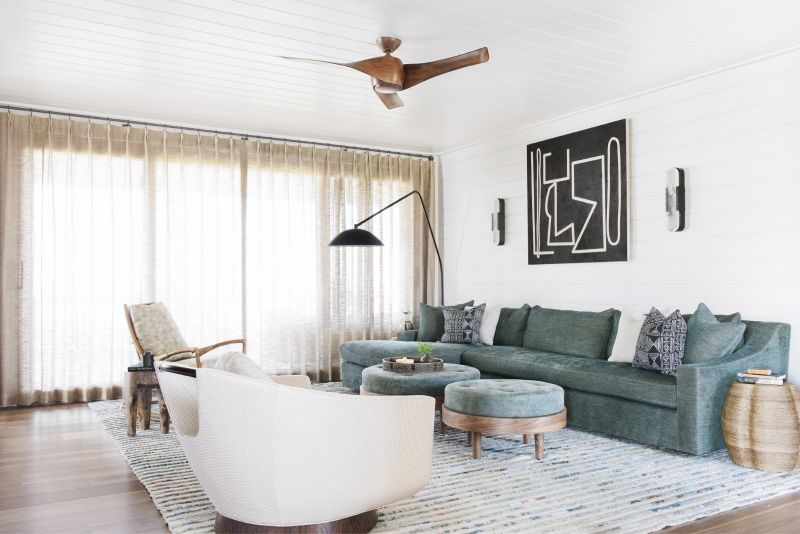 Cool Comfort: In the first-floor family room, an Amadi Carpets rug ties together an eclectic collection of furniture dominated by a Verellen sectional with matching ottomans. Kelly Wearstler for Visual Comfort sconces frame a black-and-white geometric painting by Brian Coleman from The George Gallery.