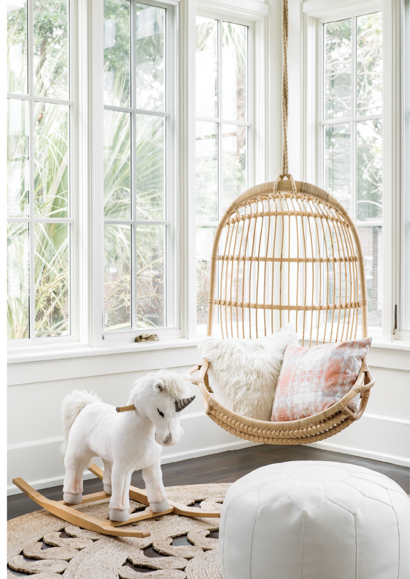 Hang Time - Kid-friendly furniture, like the Serena &amp; Lily hanging chair and white leather pouf, make this a primo seat in a light-filled playroom.  Location: South of Broad (owned by Allison and Parker Green)  Issue: March 2019, “What’s Old Is New Again”  Photographer: Katie Charlotte