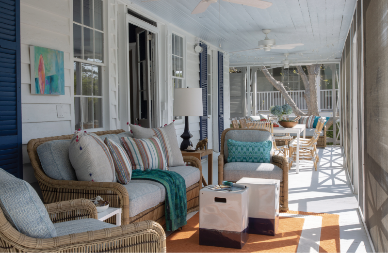 In the Zone - With its views of the Atlantic, this screened space is the most popular spot in the house. Dividing this long porch into two areas—living room in the foreground and dining for 10 in the distance—increases its usefulness and allows many people to enjoy it at once. Furnishings include classic rattan seating from Lane Venture with pillows from Candelabra, and a dining table with handmade rattan chairs from Sika Design USA that will patina to a light gray finish.  Location: Sullivan’s Island  Issue: August 2019,  “Beachy Keen”  Photographer: Julia Lynn