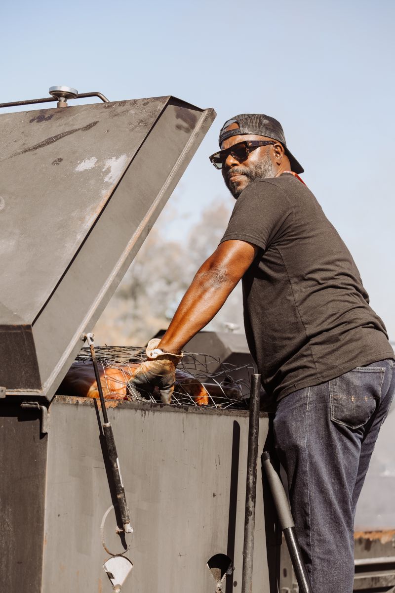 Local pitmaster Rodney Scott watches over a whole hog in the Traditional Village.