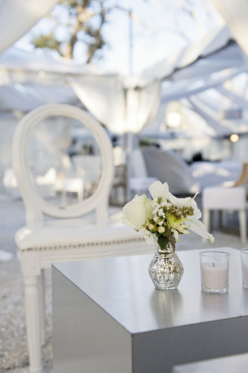 ETHEREAL GLAMOUR: Jonie LaRosse of A Charleston Bride grouped low bouquets of Dusty Miller, lisianthus, hydrangea, and roses in mercury glass vessels placed on mirrored runners.