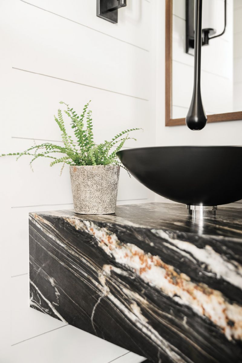 A black Alape basin and ceiling-hung faucet in the powder room