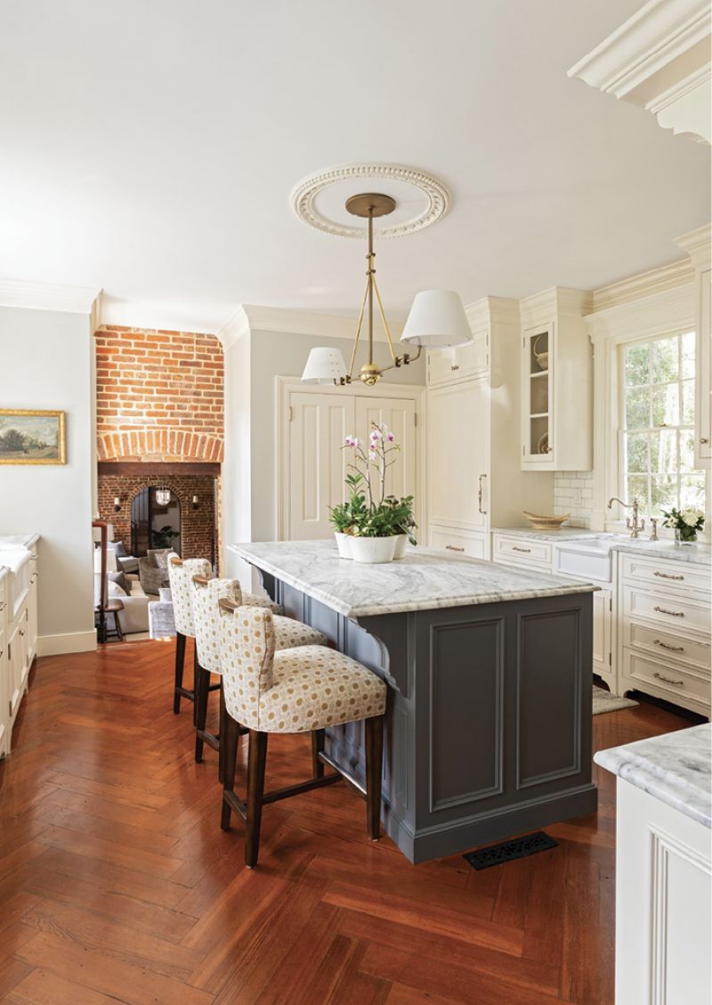 Hints of blue are carried through the house to the kitchen, where a marble countertop is hugged by three Charles Stewart stools covered in a poppy fabric with hints of warm gold.