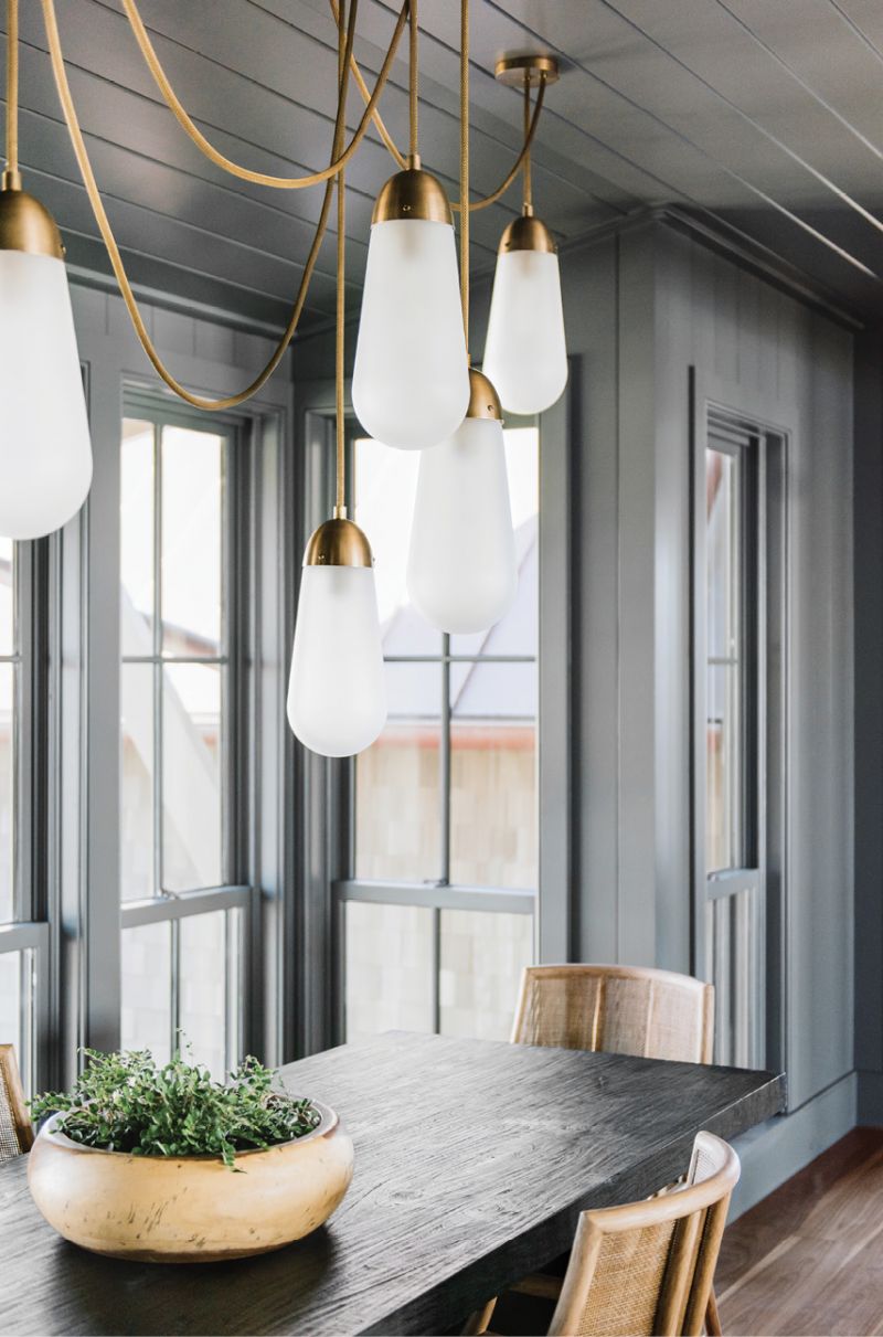 The dramatically painted dining room with a porcelain and brass chandelier by Apparatus
