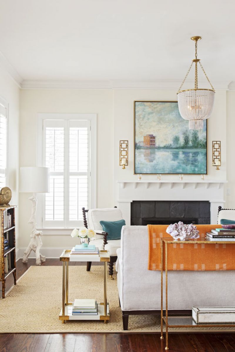 In the living room, a woven rug, creamy white walls, and neutral upholstered pieces contrast nicely with an orange throw, a violet velvet chair, and a blue-hued Linda Fantuzzo painting depicting I’On a decade ago.