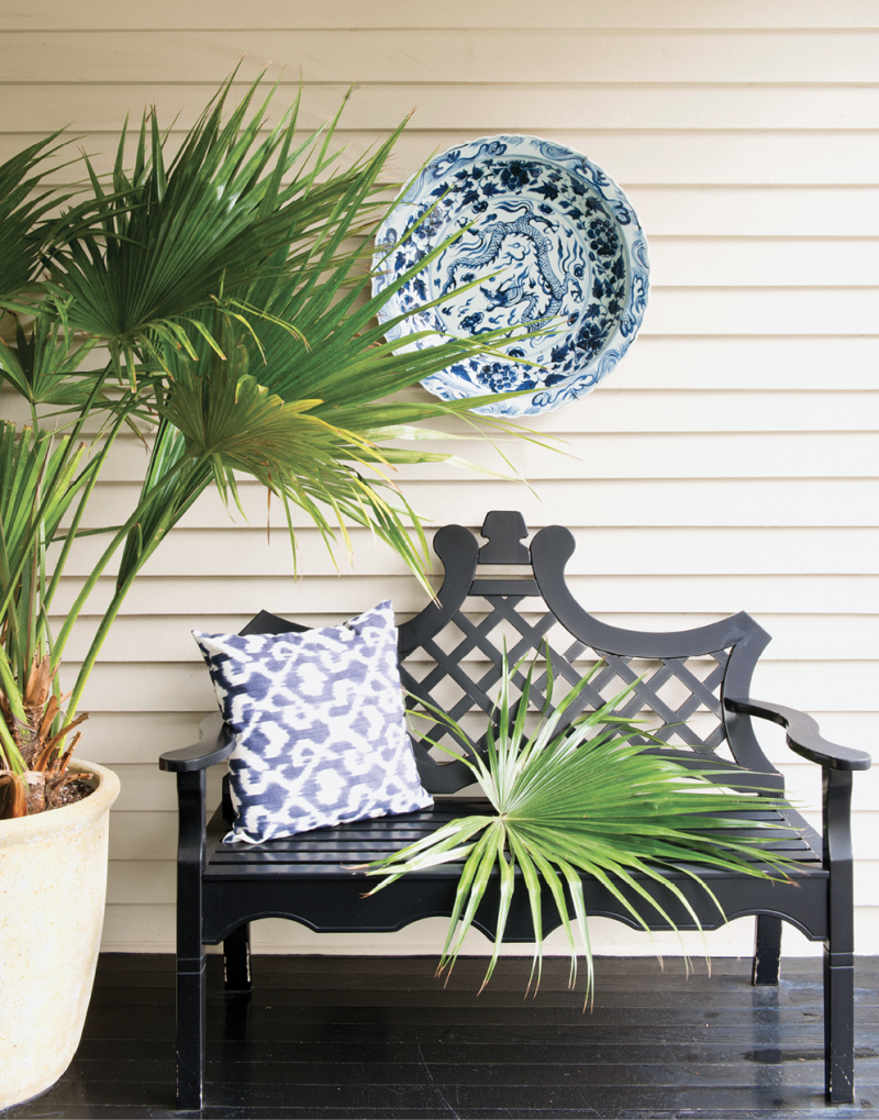 While a fanciful garden bench with a latticework back unites this porch with its garden surroundings, the blue-and-white platter and pillow bring a favorite indoor Charleston color combination outdoors.