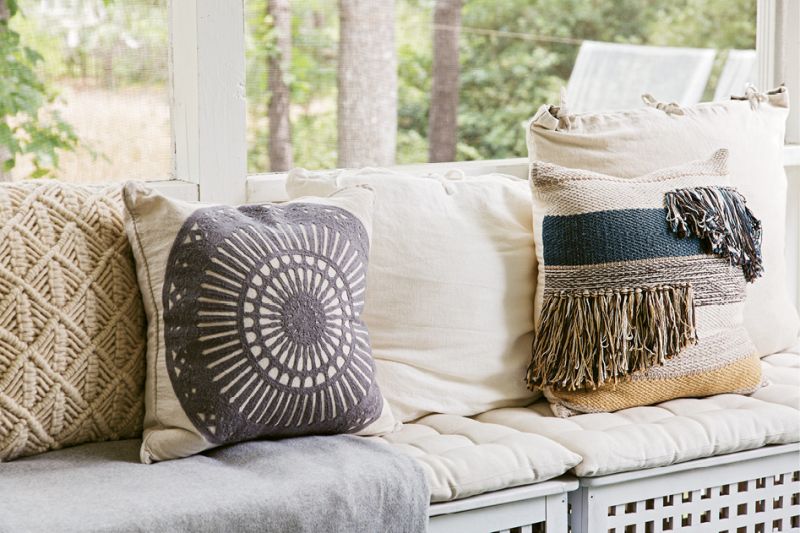 Mix &amp; Match: Therese outfitted bench seating on the screened porch with cushions and woven pillows in soft blue and cream colors.