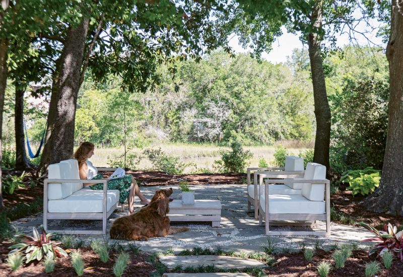 Out back, a lounge set from World Market offers marsh-side seating beneath a canopy of established trees.