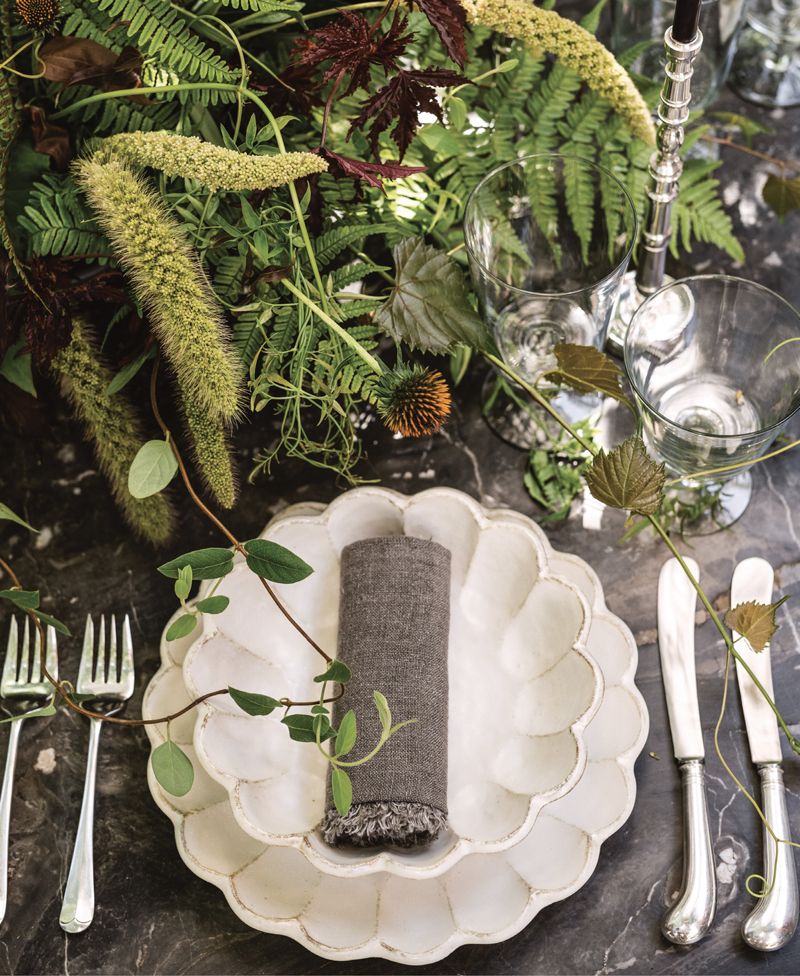 Rolls of raw washed linen and antique sterling cutlery pop against the Kaneko Kohyo “Rinka” dinnerware. Courtyard cuttings of rice paper plant, sword fern, coneflower pods, and tendrils of jasmine vine unspool in an effortlessly stylish display.