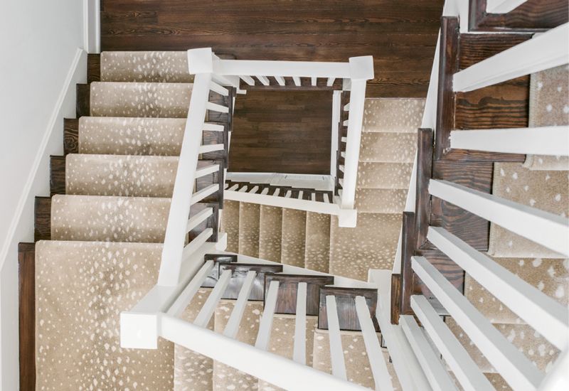 SURE-FOOTED: The team took great care to restore the existing handrail and spindles of the winding staircase. Thanks to a neutral-hued animal-print runner, socked feet and pups’ paws are padded from floor to floor.