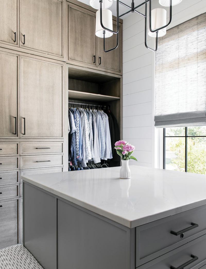 Distinctive Design’s custom cabinets and island in the large walk-in closet keep clutter at bay.
