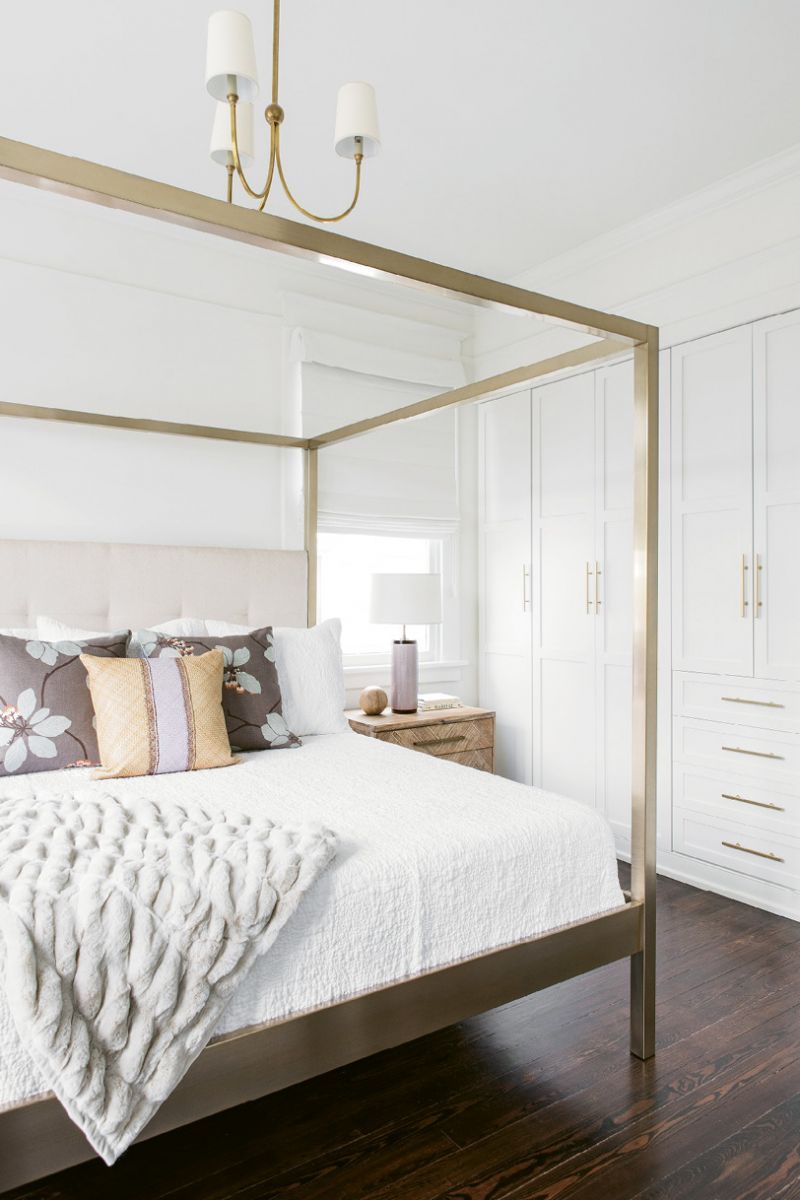 In the bedroom, sleek furnishings (like the bed and side tables from One Kings Lane, pillows and lamps from Fritz Porter, and brass chandelier by Visual Comfort from Circa) are clean-lined and serene. In lieu of a walk-in closet—which was sacrificed for a larger playroom—wall-to-wall built-ins provide plenty of storage.