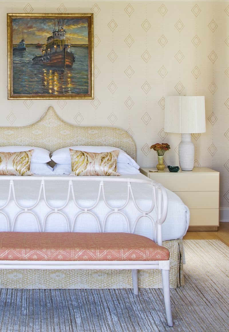 As the downstairs primary bedroom was converted to a den and home gym, this second-floor suite received full posh treatment, including Allen’s gold hand-stenciling on a grasscloth wall covering, a first for Hranowsky. The diamond pattern is echoed in the headboard and bed skirt fabricated in a jacquard silk by Jennifer Shorto and bench found at 1stDibs and recovered in Carolina Irving Textiles “Zig Zag” fabric in “coral.”