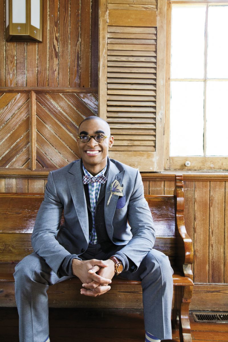BENCH WARMER “Campbell Flap Suit” in wool with horn buttons, “John T” blue and green tartan plaid oxford, “Berwick” cardigan, bow tie, and “Zach” belt, all from Billy Reid. The Hill-side’s polka-dotted pocket square from Indigo and Cotton.  Bulova’s Accutron Exeter watch with rose gold accents and brown leather band from REEDS Jewelers. Tortoise shell glasses from SEE. Boutonniere from Tara  Guérard Soiree. Nigel Knox&#039;s “Archibald” striped socks from M. Dumas and Sons.
