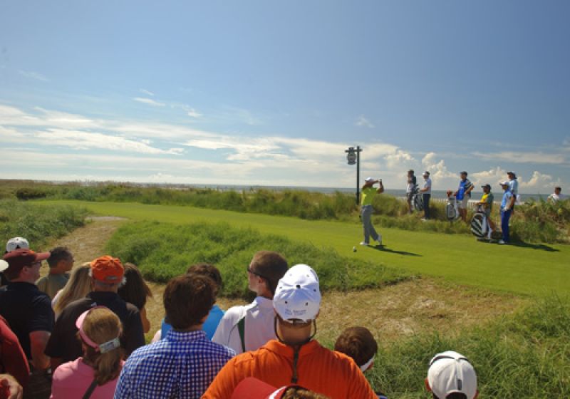 After saving par on the par 3 17 Tiger crushes his drive on 18 with the Atlantic and a few people watching.