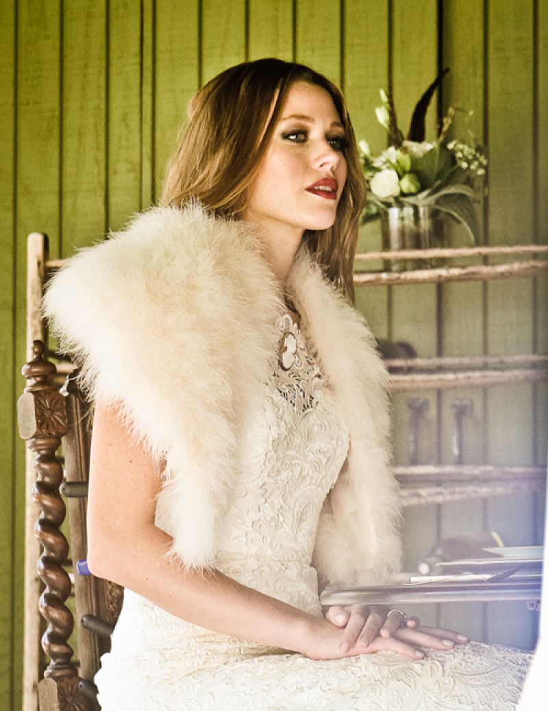 Callie Tein’s  “Nila” gown with bateau neckline, cap sleeves, and Italian lace overlay, and boa, both from Modern Trousseau. Vintage cameo pin from Out of Hand. Photograph by Jonathan Balliet