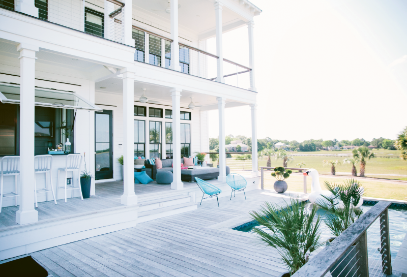 The patio is tiered so that pool activity won’t obstruct the striking river views; the flip-open window on the indoor-outdoor bar allows for easy access to the kitchen.