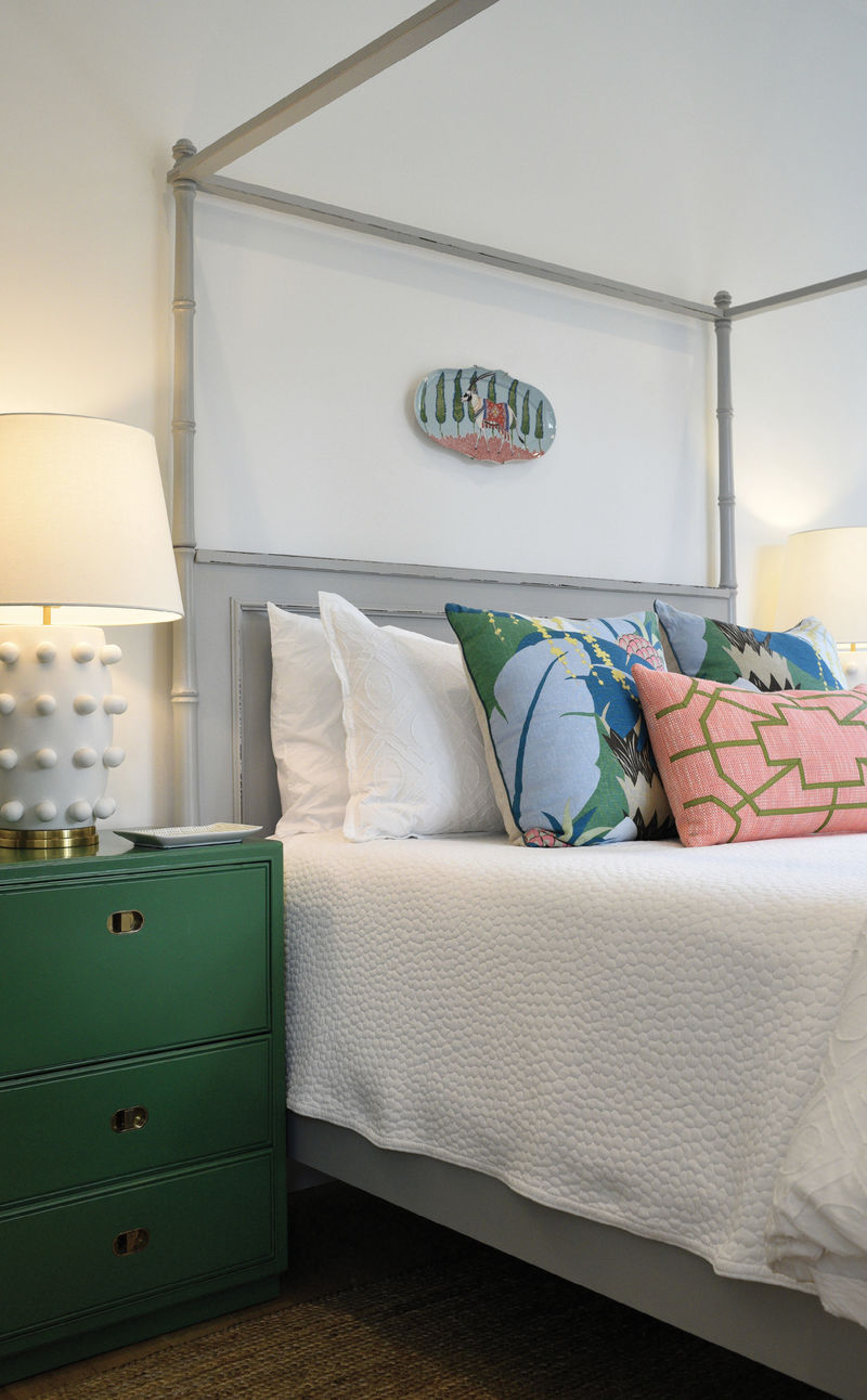 PASTEL PERFECT: The Braggs’s 15-year-old daughter, Ella, is “very opinionated” about her room, helping Alix design the space by combining the reproduction bamboo tester bed with the pillows in Schumacher’s Ananas print, both from Acquisitions Interiors, and her mom’s vintage side tables. The doors of the green-lacquered beauties fold down to provide the perfect spot for charging her phone and squirreling away clutter.