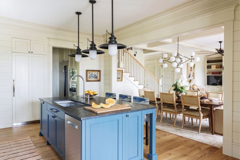 COUNTER CULTURE: A soapstone-topped island, painted in “Silent Night” from PPG, ties the living-dining room into the spacious kitchen. Just beyond the glass doors is the outdoor kitchen and dining room, where Martha and Paul enjoy entertaining friends and family.