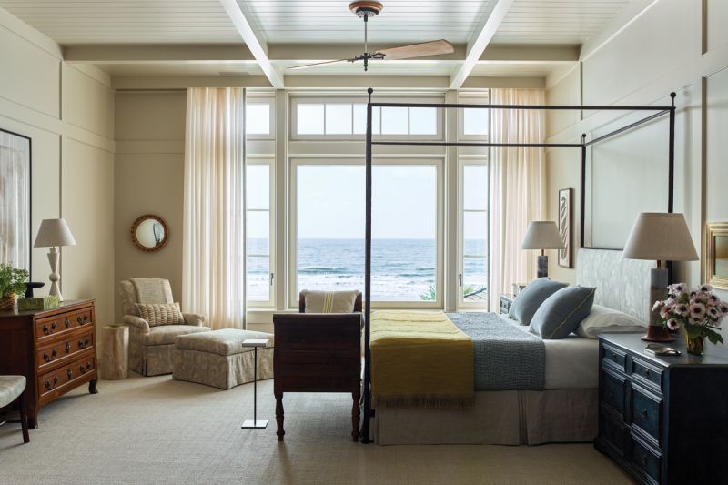 An iron four-poster bed and antique wooden chests ground the light, airy bedroom.