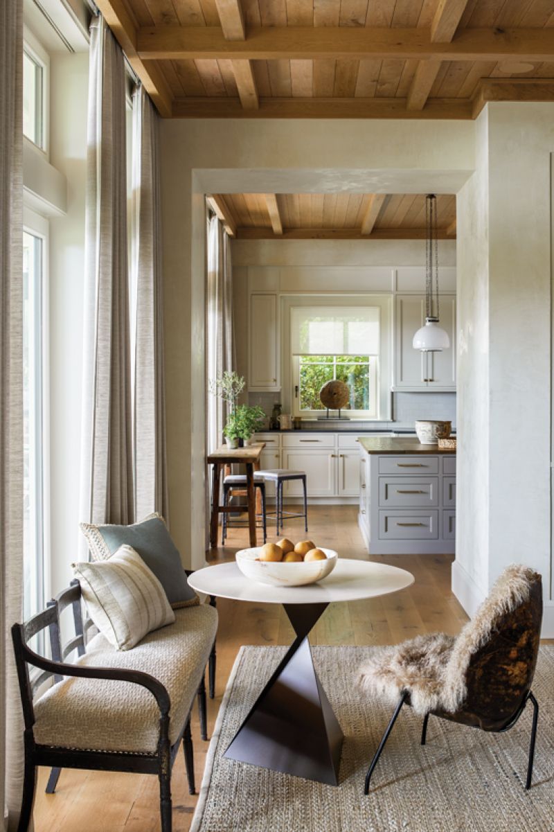 An adjoining cocktail nook with ocean views features a mid-century turtle shell chair upholstered with shearling, juxtaposed with the angular Tom Faulkner steel and stone table.