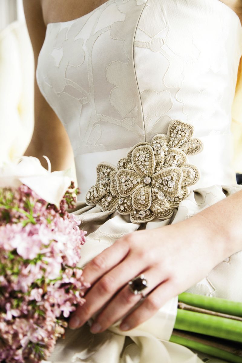 BRING IT IN: “Regan” ball gown in silver silk brocade and the “Pansy” belt, both from Modern Trousseau. 14K white gold ring with smoky quartz center stone and white and chocolate accent diamonds from Skatell’s. Amaryllis bouquet by WildFlowers, Inc.