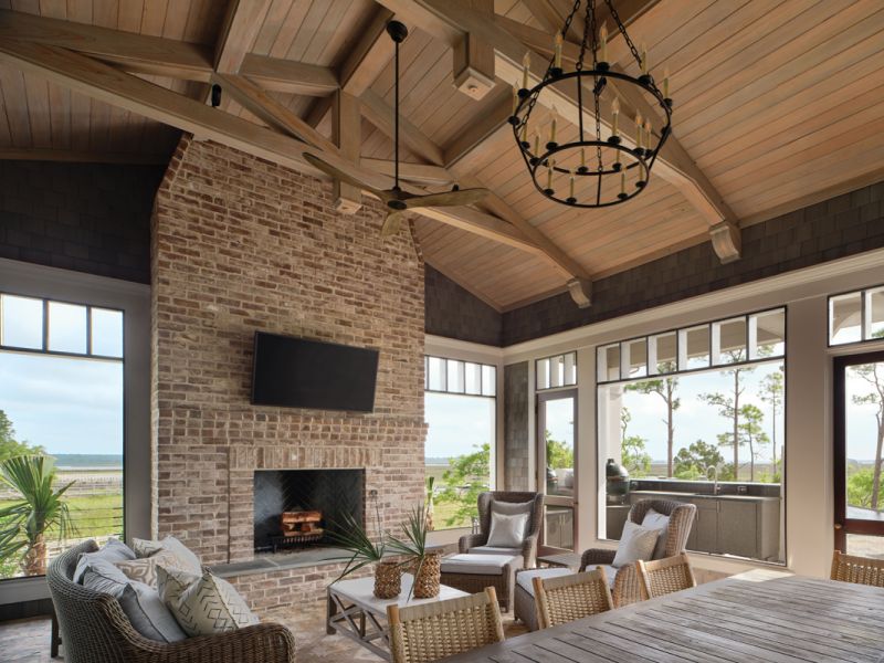 The large screened porch with its massive brick fireplace and outdoor kitchen is the family’s favorite room for most of the year. Kingsley Bate wicker furniture surrounds the hearth, while a candelabra-style “Darlana” chandelier from Visual Comfort illuminates the space.