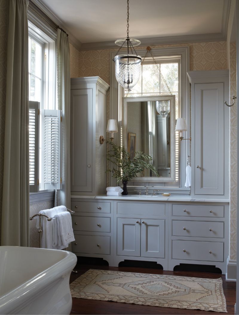 Morning Glory: A 19th-century bell jar fixture from Tucker Payne Antiques lights the bathroom, with its elegant custom cabinetry by F.M. Jessen Inc. in “Gimlet” by C2 Paint.