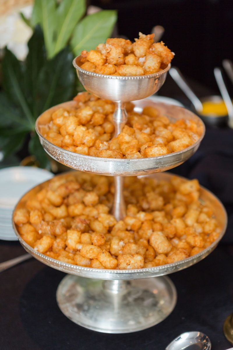 Three-tiers of tater tots on a silver pedestal, ready to be served with caviar.