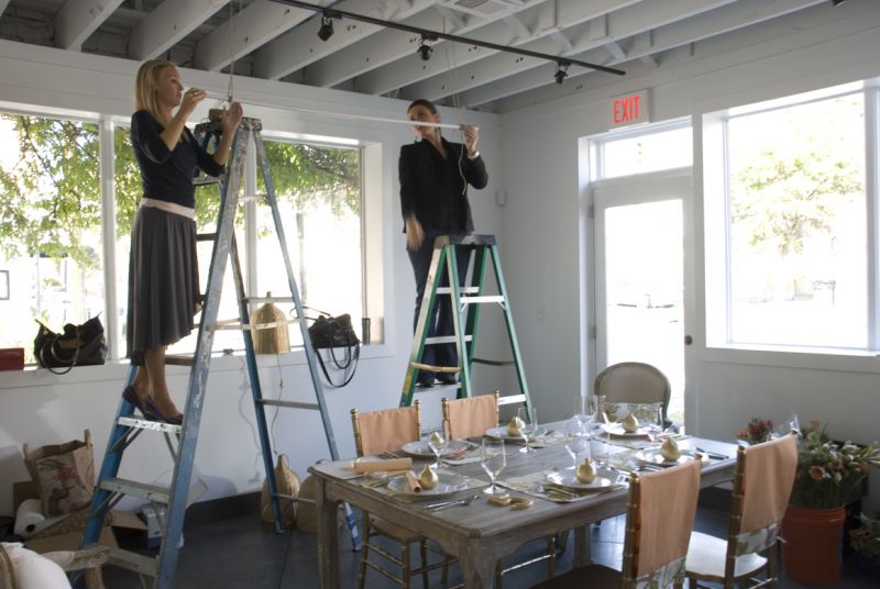 Melissa Barton (right) and Leigh from A Charleston Bride tried a few ways to get the wicker lamps to hang at just the right height. In the end, they just hung them from the rafters at stems. I love shooting there! Everything’s on casters and can be rolled away, the light is great, and the backdrop is so clean. No wonder it’s primo for holding events.
