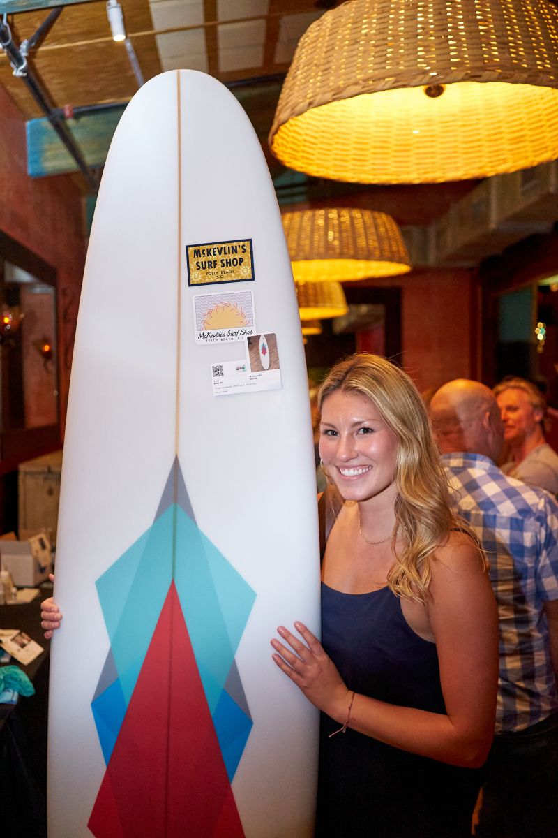Harper Winicov, clinic coordinator and surf instructor for Waves 4 Women, shows off the new surfboard she won in the silent auction.