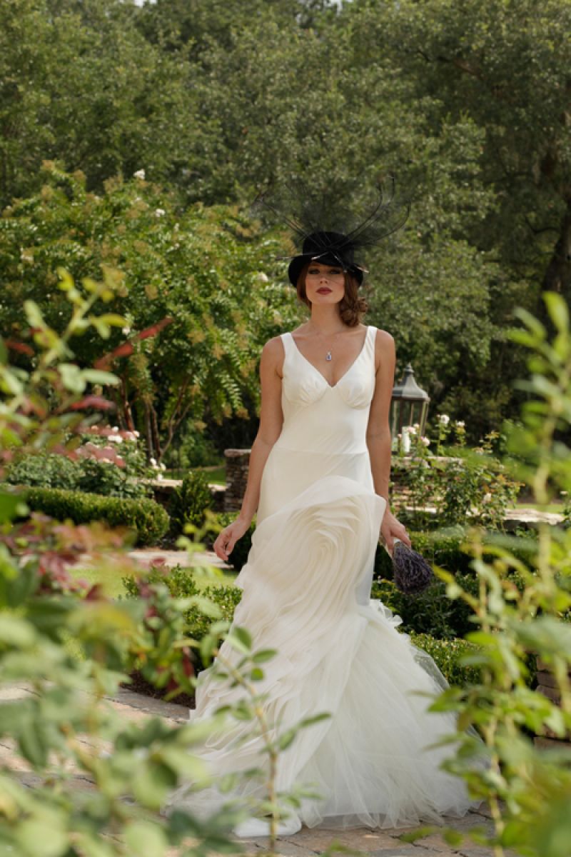 Vera Wang’s “Janice” gown with V-neck and deconstructed tulle and organza details and embellishments from Maddison Row. “Theodora” felt top hat with feathers and veil from Magar Hatworks. Silver necklace with tanzanite center stone and diamonds from REEDS Jewelers.