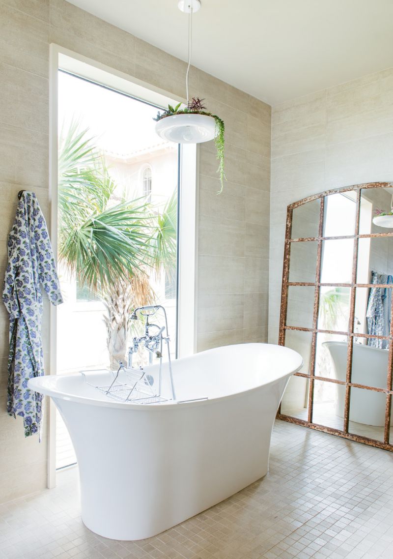 In the bath, the large mirror, made from a salvaged window, reflects the beach and the palm trees.