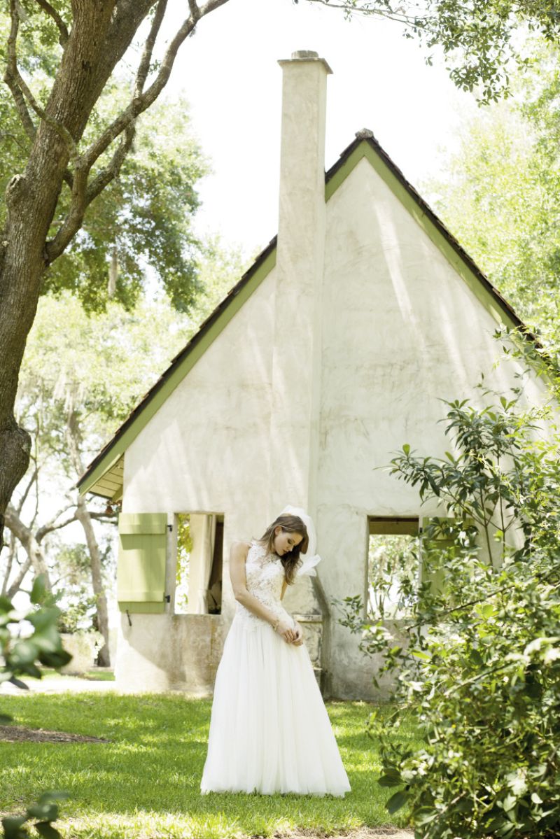 Badgley Mischka Bride’s “Dolley” silk satin gown with cowl neck and sheer back panel with crystal detailing from White on Daniel Island. Treats for Tresses feather, gold butterfly, and lace hair accent from Article 5 Salon and Boutique. SLANE’s “Calypso” white topaz earrings in sterling silver from REEDS Jewelers.