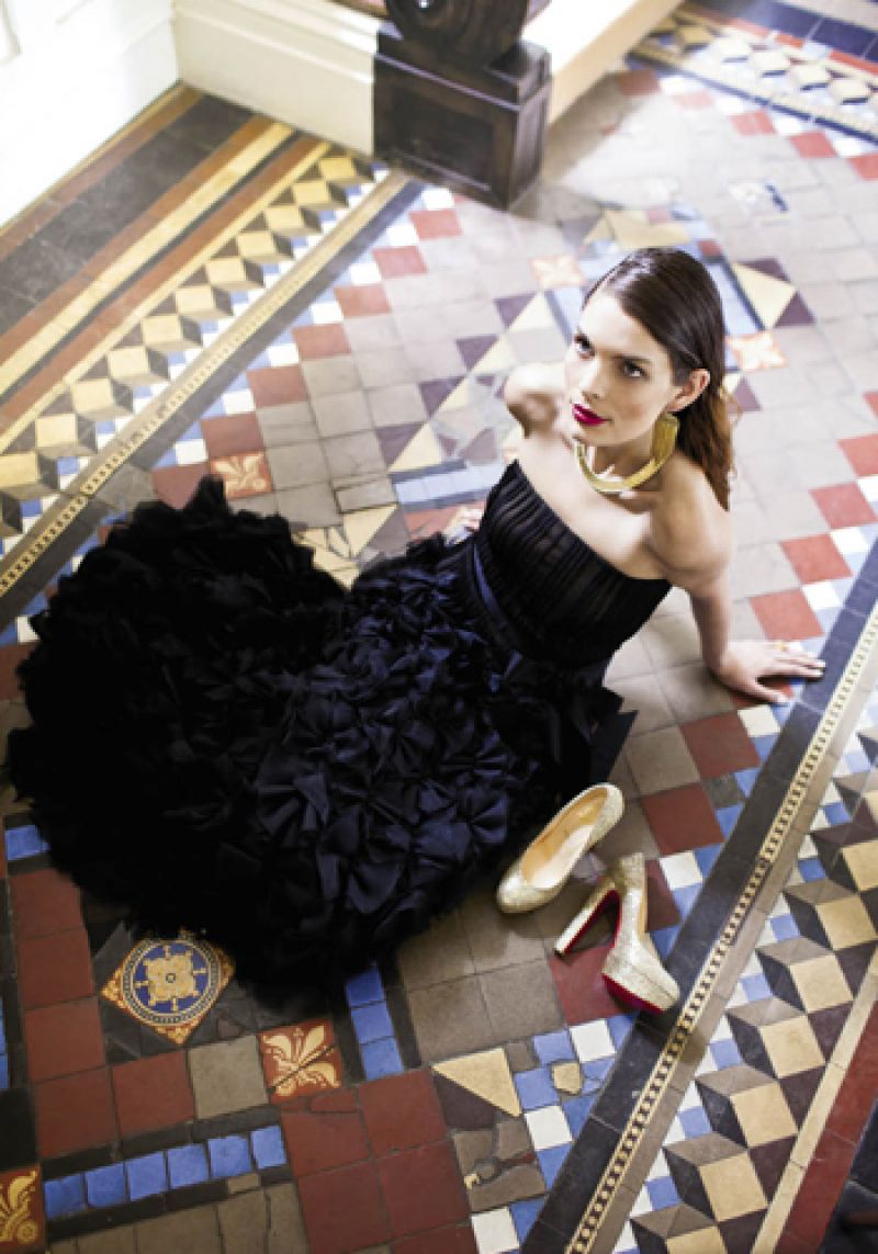 Tadashi Shoji silk gown with pleated top, skirt of appliqué silk flowers, and silk belt, $808, and Melanie Auld “Sylvia” gold chandelier earrings with diamonds and amethysts, $310, both at Anne’s; “Cleon” 18K gold and diamond necklace, $12,990 at Skatell’s; Christian Louboutin “Bibi” glitter platform pumps from the “Classique” collection, $795 at Bob Ellis Shoes.