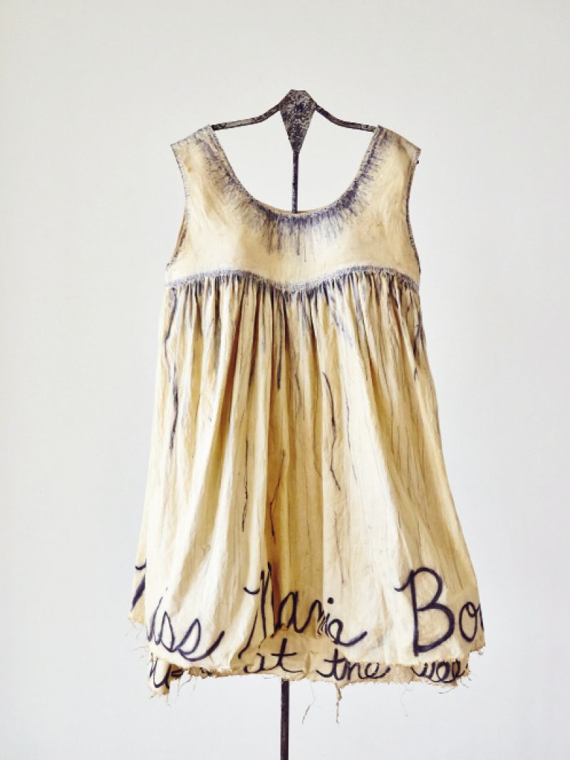 At the 701 Center for Contemporary Art, the new Madame Magar collection of muslin and canvas frocks hangs on pulleys and  hooks. As part of the exhibit, Charleston-based designer Leigh Magar has created a temporary studio workshop within the gallery space so  visitors can see her sewing, dyeing, and adding penciled lettering to the dresses.
