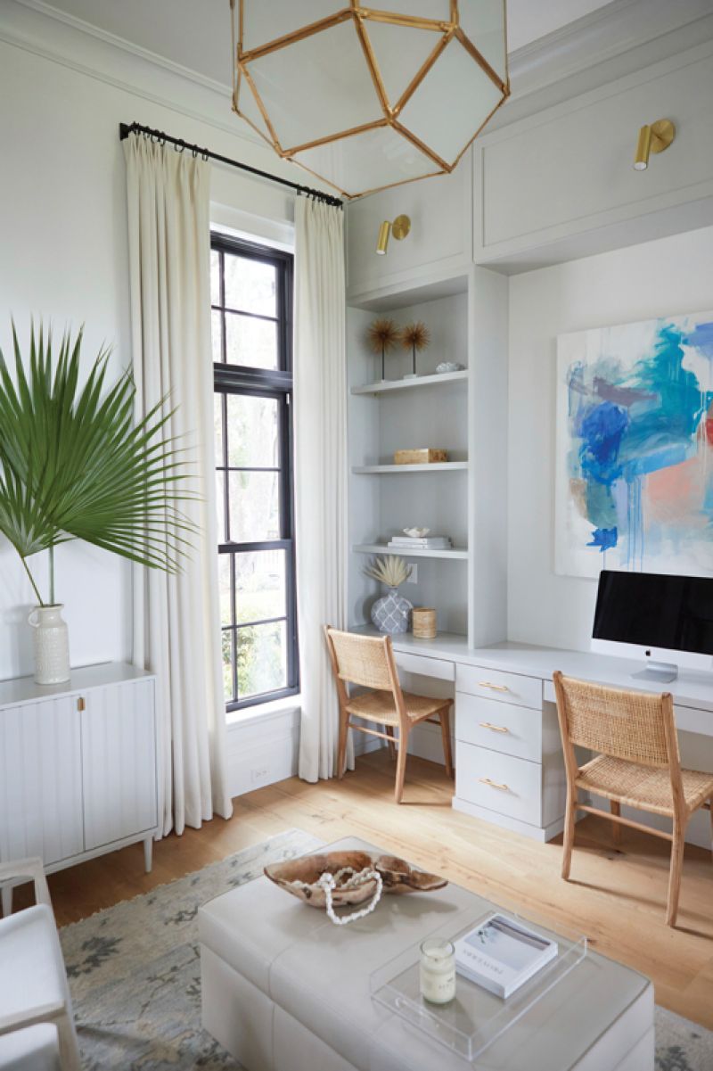 work it: Situated just off the main living area and separated by a glass wall, this kids’ homework space feels fresh and bright. A Wildwood Home console painted in Sherwin Williams “Front Porch” fits three desks, one for each child, and provides storage for school supplies and games. Accents such as artwork from Charleston Artist Collective, a brass pendant light from Visual Comfort, and a cream rug from Loloi tie it in with the first-floor decor.