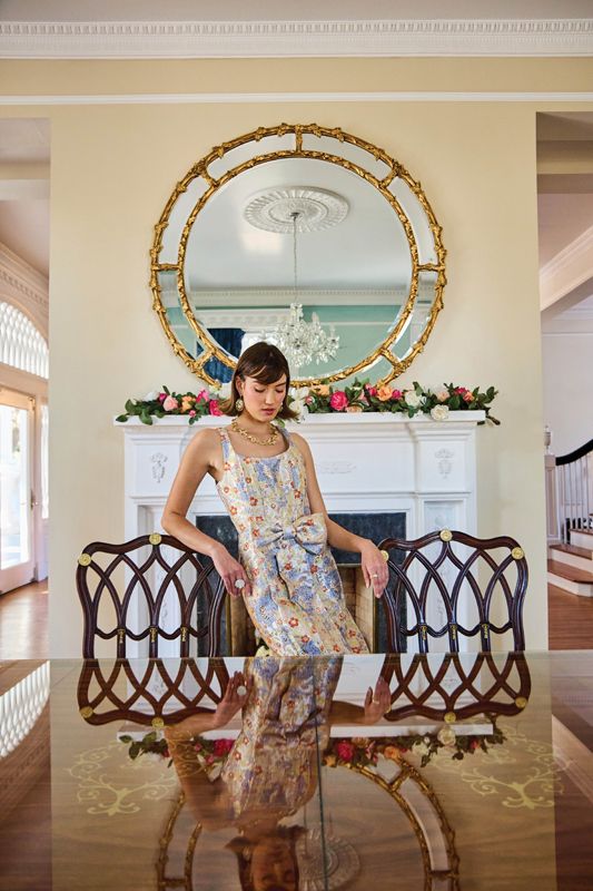 <strong>Time to Shine:</strong> Mestiza New York “Audrey” metallic jacquard bow-front midi dress, $475 at <a href="https://www.dillards.com/p/mestiza-new-york-audrey-metallic-jacquard-scoop-neck-sleeveless-bow-front-midi-dress/519354744" target="_blank">Dillard’s</a>; Capucine De Wulf “Meadow Wildflower” necklace, $325, “Villandry” collection “Lattice” earrings, $225, “Bunny” ring, $395, and “Fleur Vine” ring, $98, at <a href="https://capucinedewulf.com/collections/rings/products/villandry-fleur-vine-ring-mop" target="_blank">Juliska</a> - (Prop) Garland with blooms from <a href="https://www.weddingflowersforrent.com/collections/garlands/products/garland-with-blooms" target="_blank">Wedding Flowers For Rent</a>