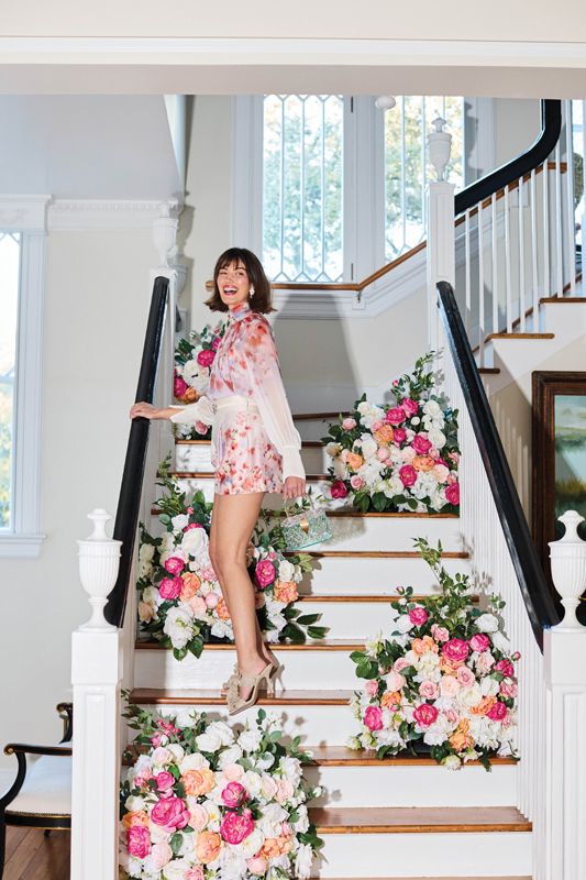 <strong>Flower Power: </strong>Zimmerman “Crush Smock” blouse and shorts in “Scarlet Floral,” $595 and $750, at <a href="https://www.gwynns.com/products/crush-smock-blouse-scarlet-floral-0?_pos=35&amp;_sid=5e7801f23&amp;_ss=r" target="_blank">Gwynn’s of Mount Pleasant</a>; J. Melissa Designs “Floral Drop” earrings, $88 at <a href="https://rhodesboutique.com/" target="_blank">Rhodes Boutique</a>; Simon G. “Fallen Leaves” diamond ring, $3,170, and Rebeka Hakimi gold and diamond band, $4,500, at <a href="https://diamondsdirect.com/" target="_blank">Diamonds Direct</a>; “Kelly” vintage-style acrylic bag, $158 at <a href="https://www.jujuloves.com/products/1950-vintage-style-spearmint-ice-crystal-acrylic-lucite-box-clutch-bag" target="_blank">JuJuLoves.com</a>; Gianni Bini “Hardaway” sandals in “sand gold,” $90 at <a href="https://www.dillards.com/p/gianni-bini-hardaway-mesh-fabric-ruffle-dress-sandals/518708736" target="_blank">Dillard’s</a> - (Props) Grounded floral arch from <a href="https://www.weddingflowersforrent.com/collections/garlands/products/grounded-floral-arch-regular" target="_blank">Wedding Flowers For Rent</a>